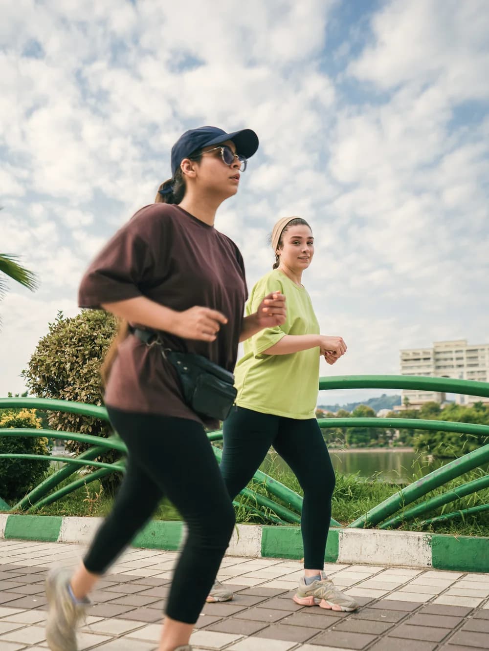 Two women jogging together along a lakeside path