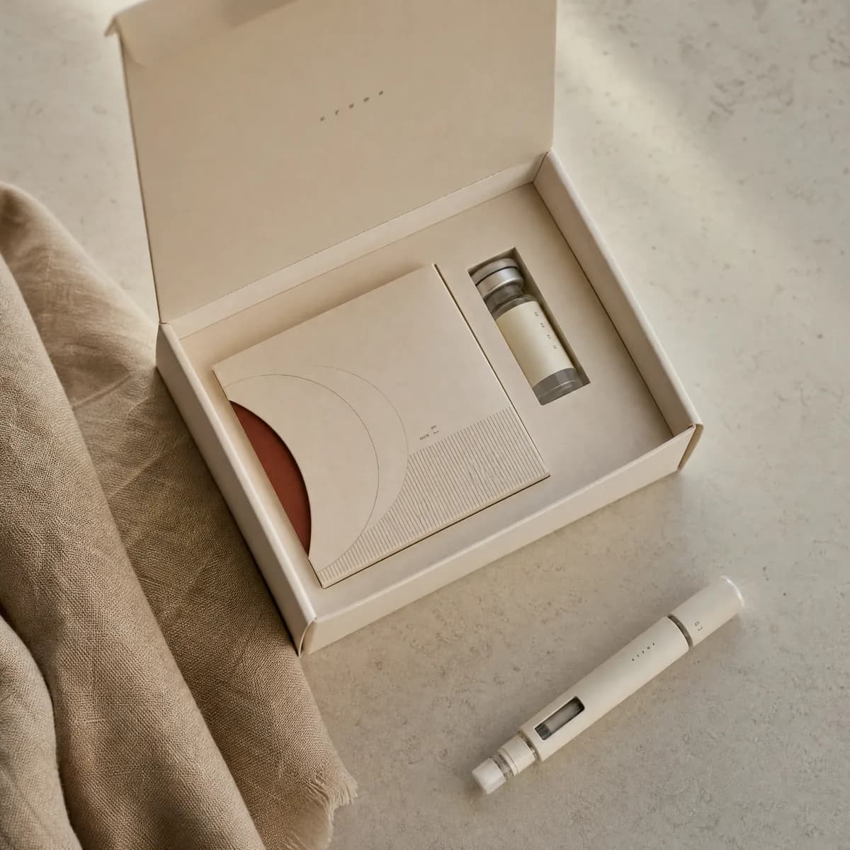 An opened Ryo kit with vial and pen on linen